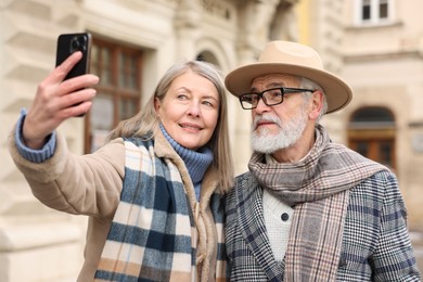 Photo of Lovely elderly couple taking selfie on city street