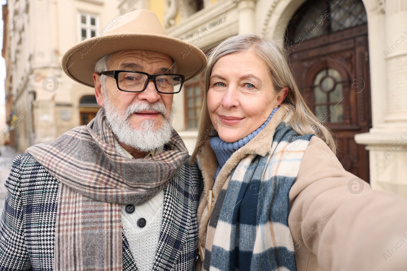 Photo of Lovely elderly couple taking selfie on city street