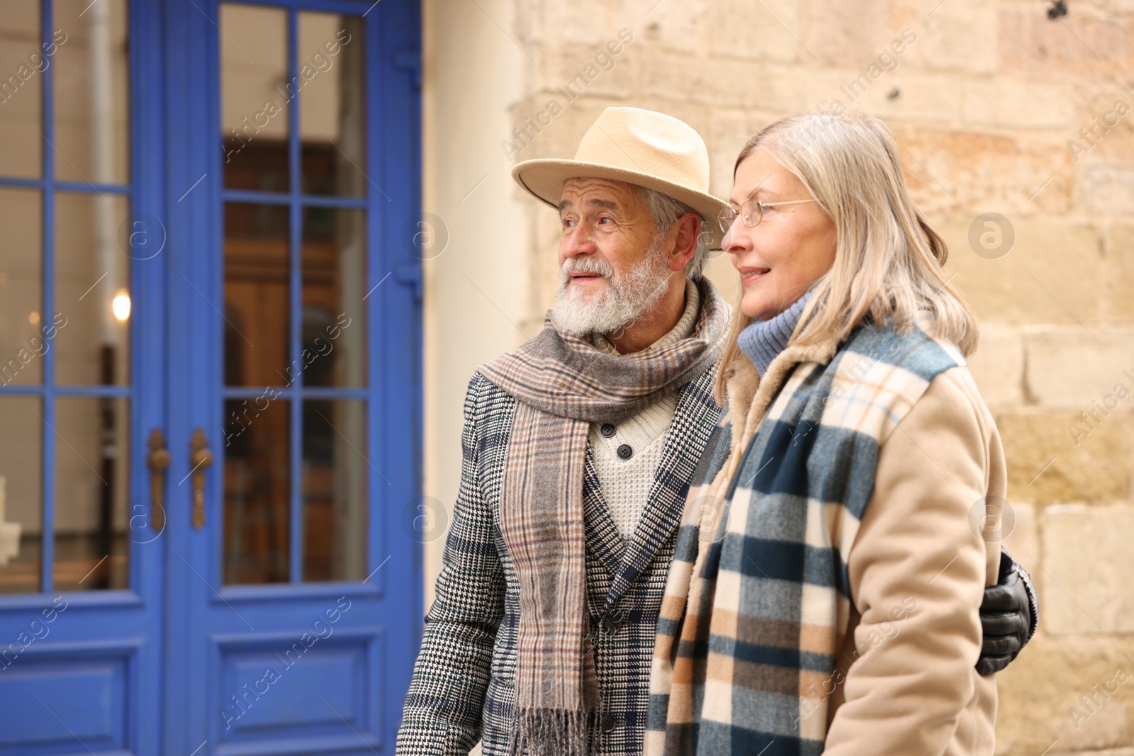 Photo of Happy elderly couple walking on city street. Space for text