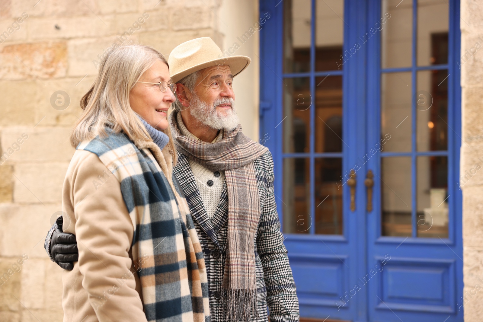 Photo of Happy elderly couple walking on city street. Space for text