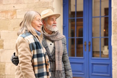 Photo of Happy elderly couple walking on city street. Space for text