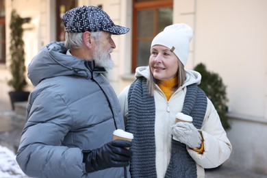 Photo of Happy elderly couple with paper cups on city street