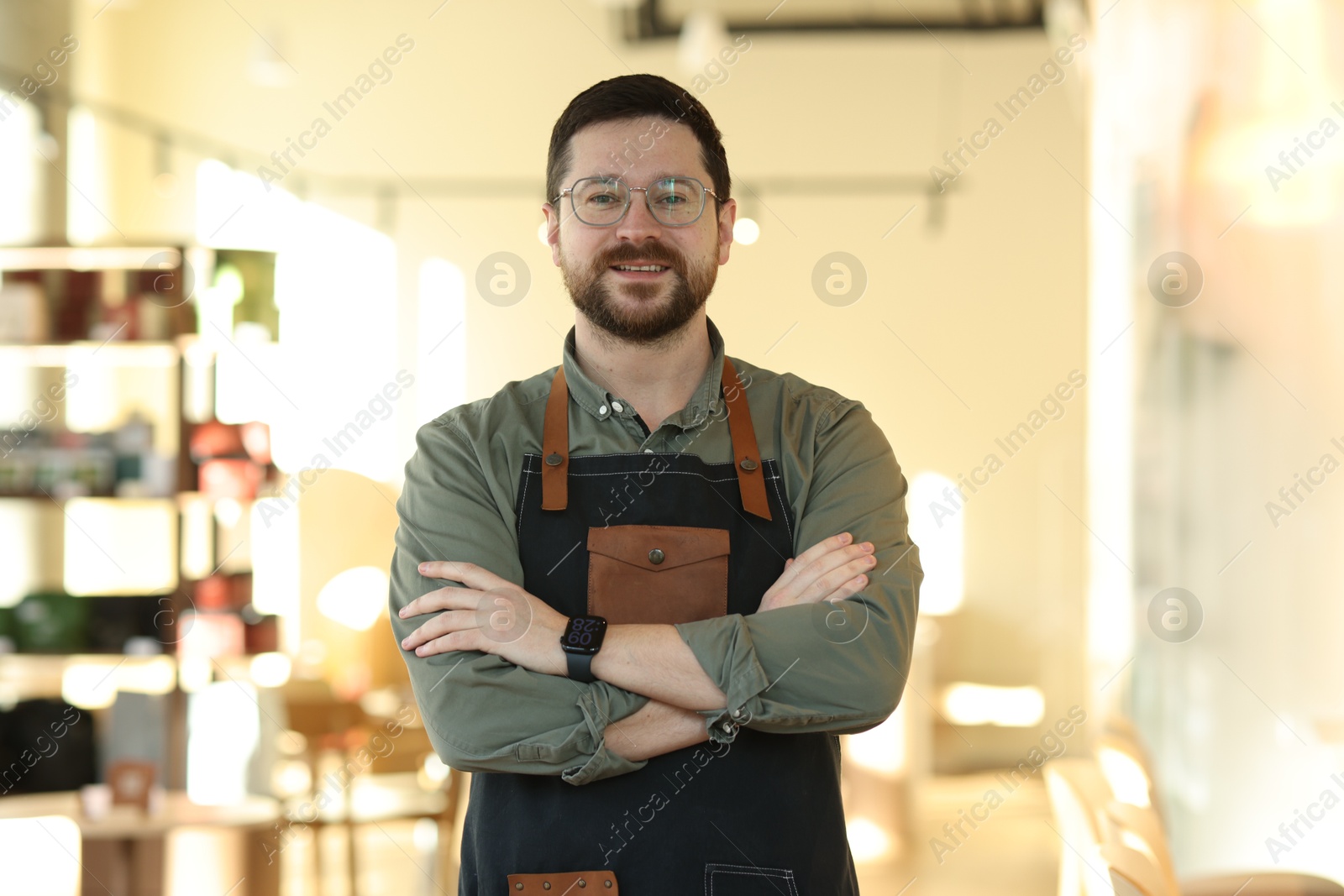 Photo of Portrait of smiling business owner with crossed arms in his cafe