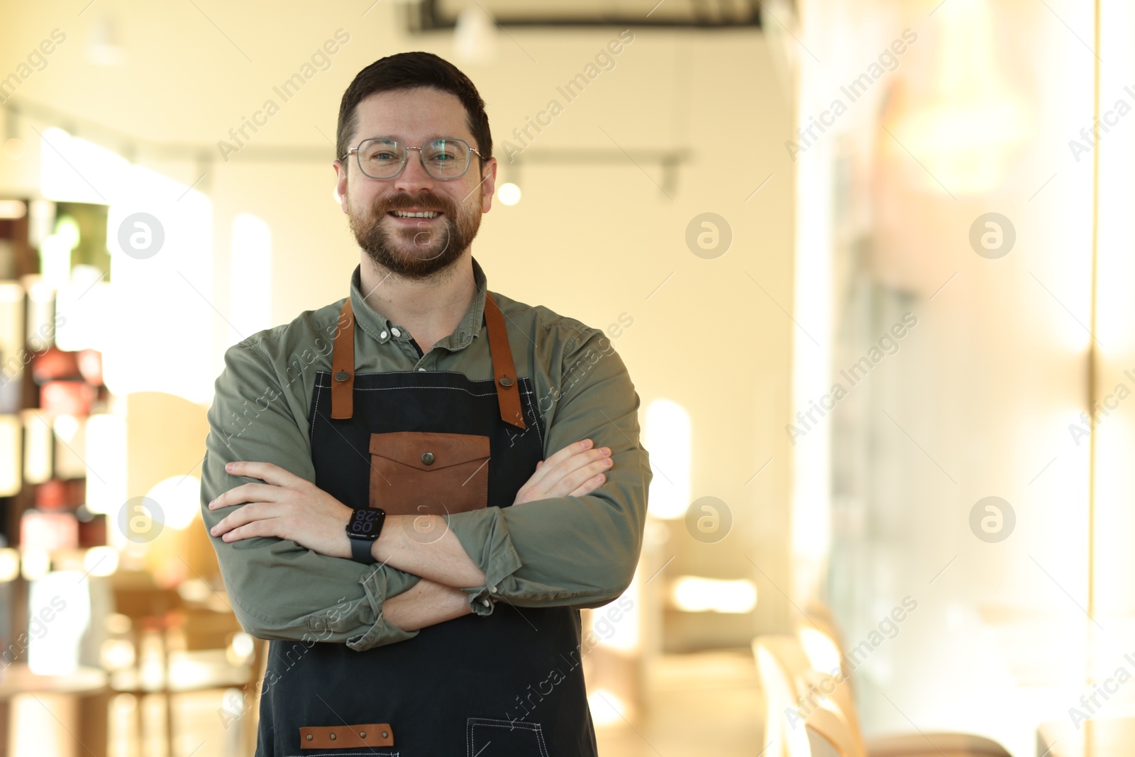 Photo of Portrait of smiling business owner with crossed arms in his cafe. Space for text