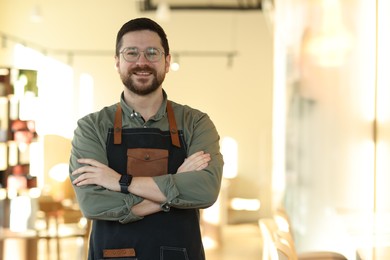 Photo of Portrait of smiling business owner with crossed arms in his cafe. Space for text