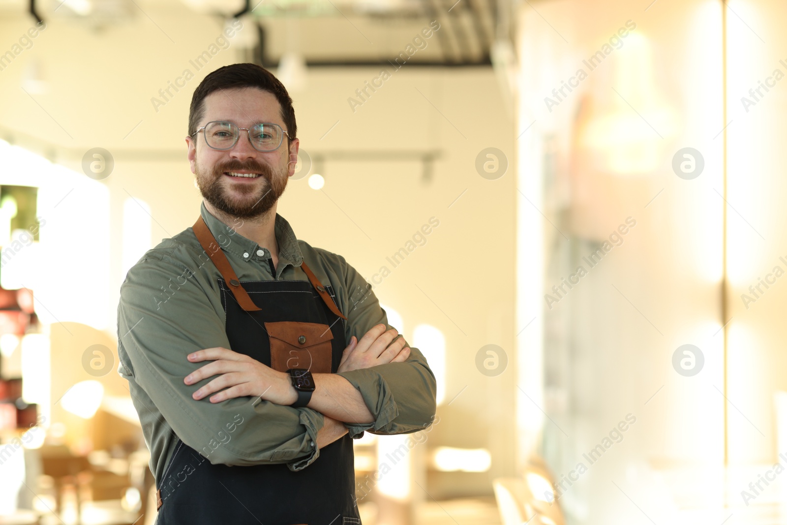 Photo of Portrait of smiling business owner with crossed arms in his cafe. Space for text