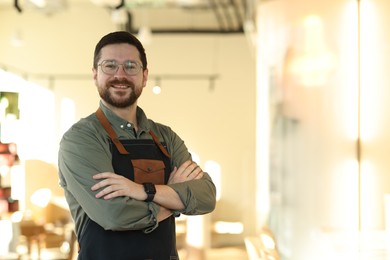 Photo of Portrait of smiling business owner with crossed arms in his cafe. Space for text