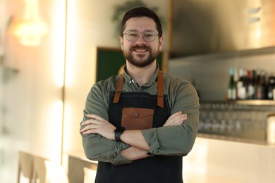 Photo of Portrait of smiling business owner with crossed arms in his cafe