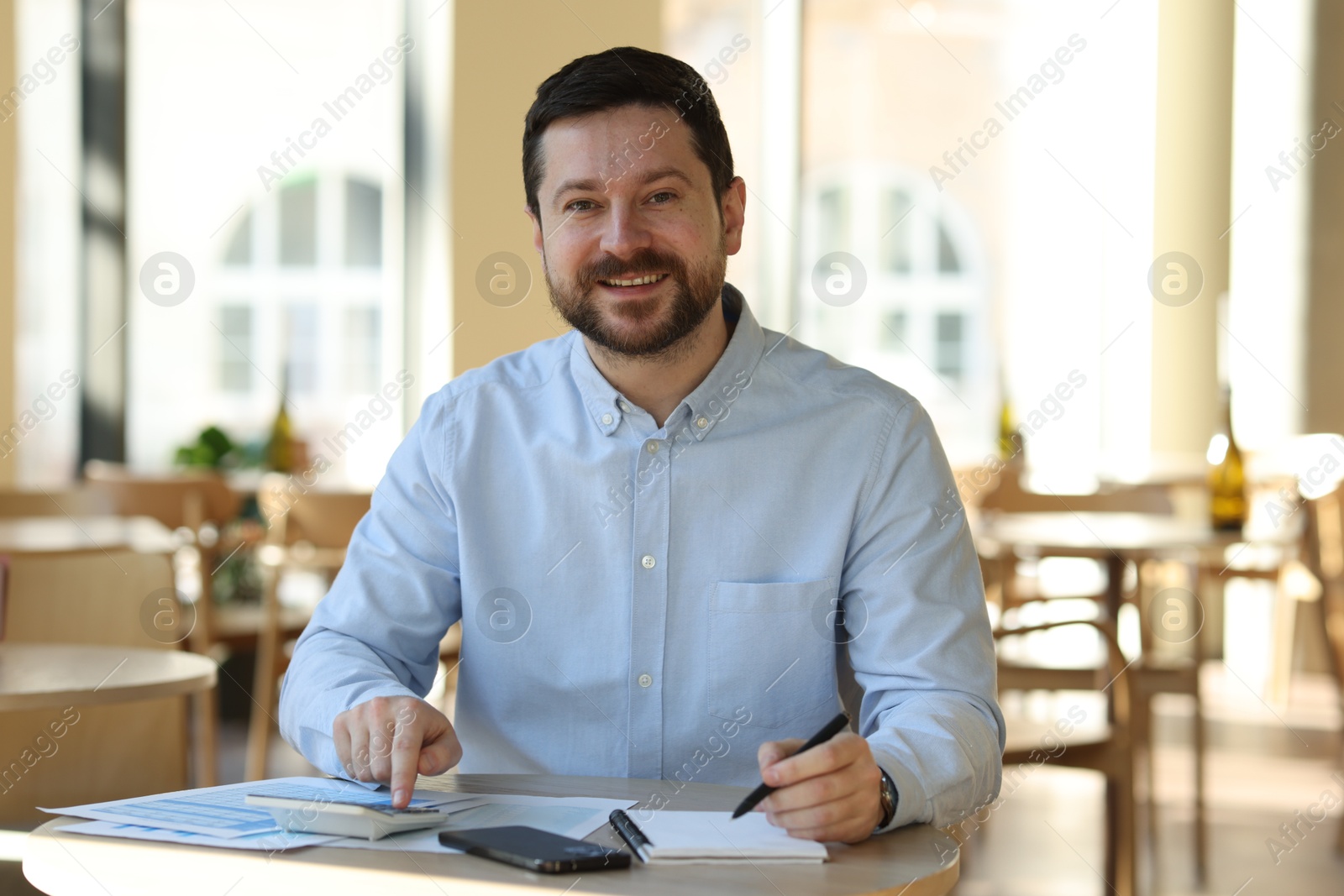 Photo of Portrait of smiling business owner at table in his cafe