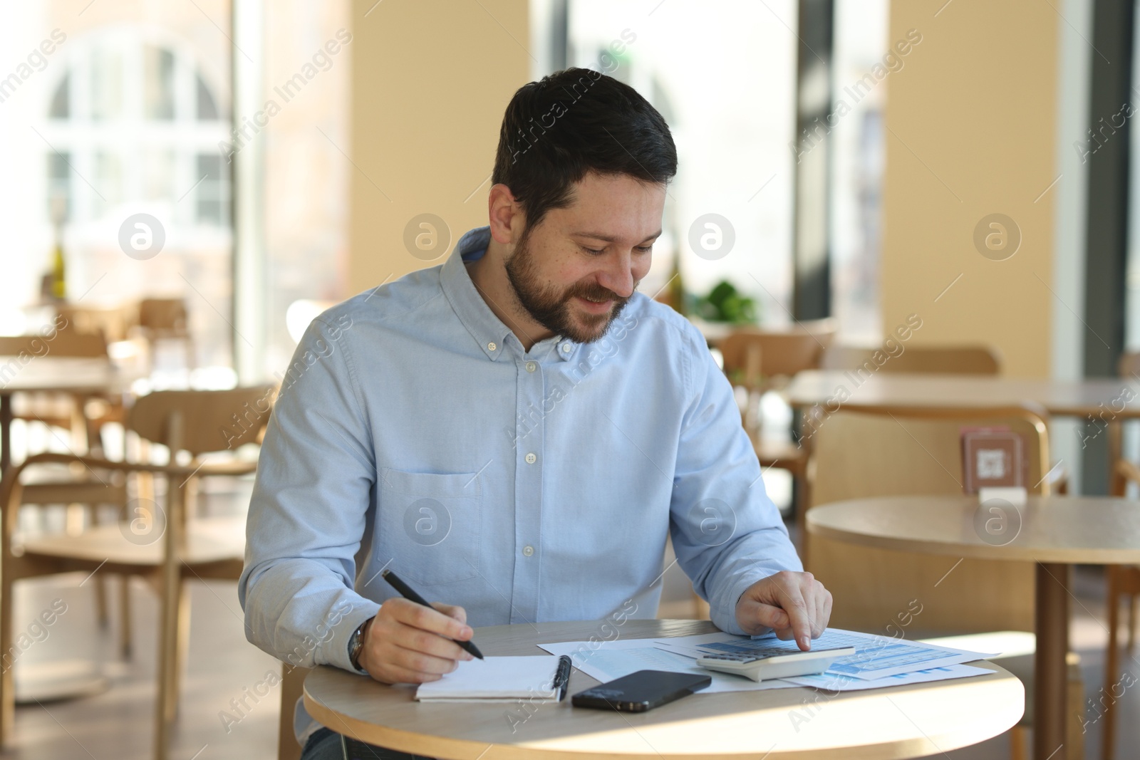 Photo of Handsome business owner doing paperwork at table in his cafe