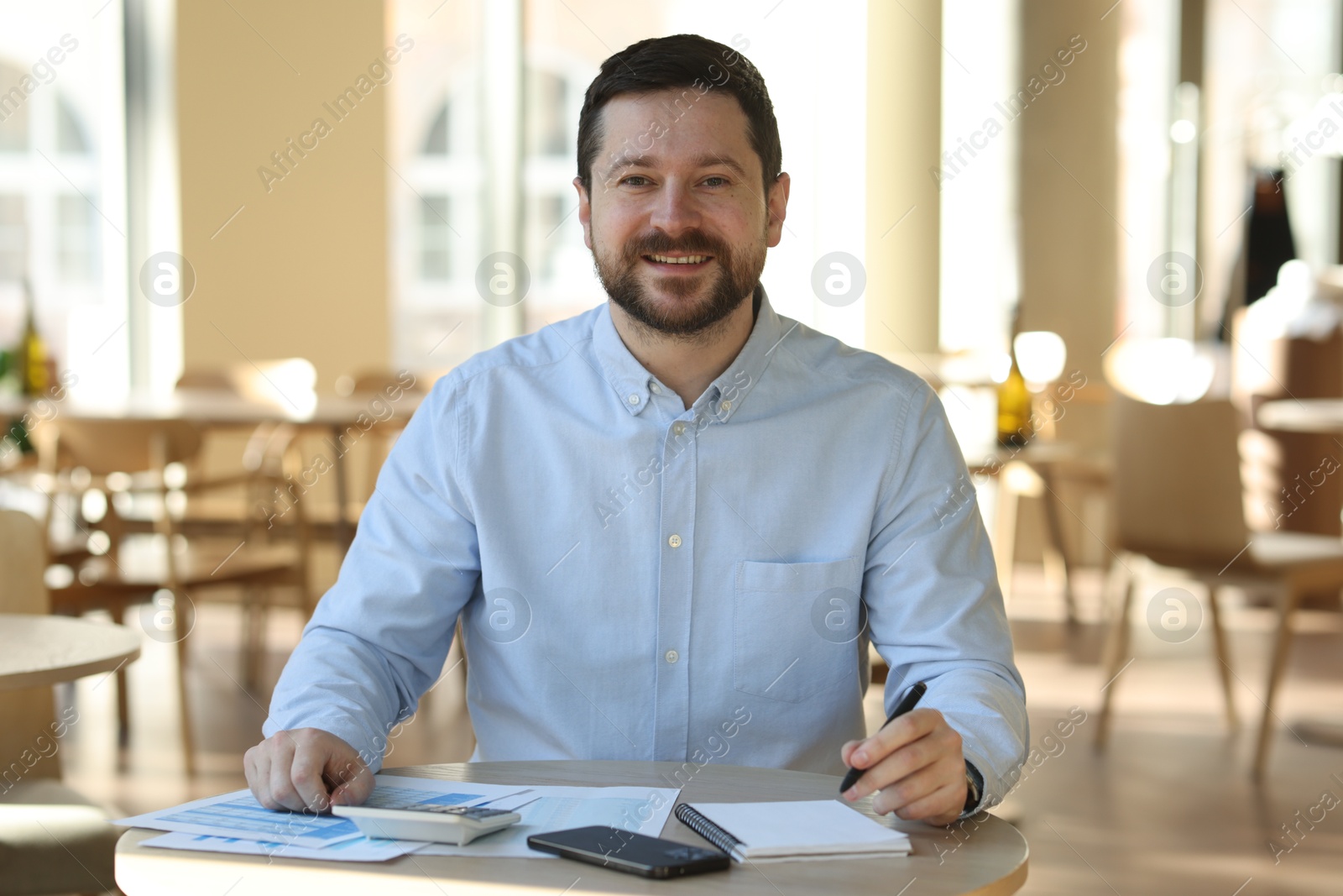 Photo of Portrait of smiling business owner at table in his cafe