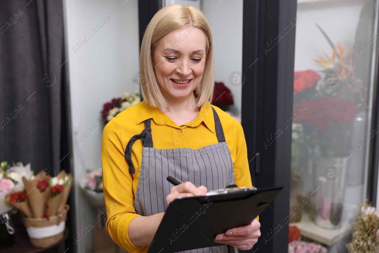 Photo of Business owner with clipboard taking notes in her flower shop