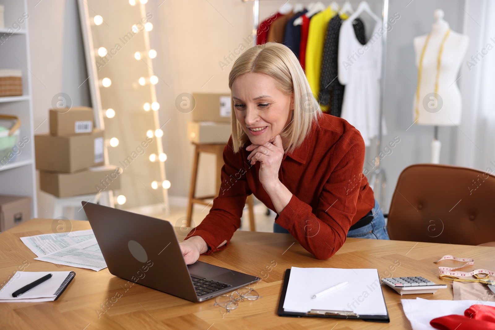 Photo of Business owner working on laptop at table in her tailor shop