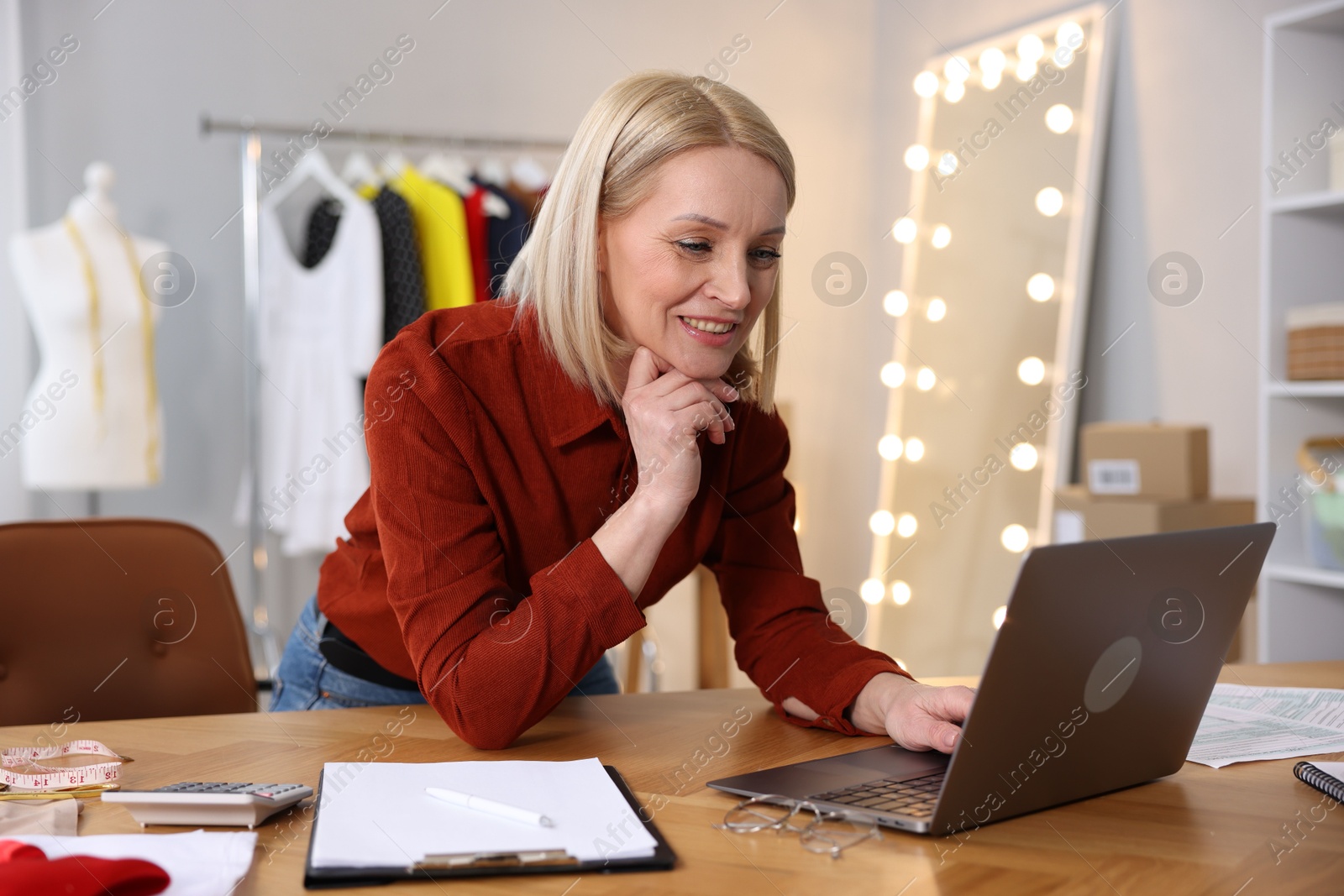 Photo of Business owner working on laptop at table in her tailor shop