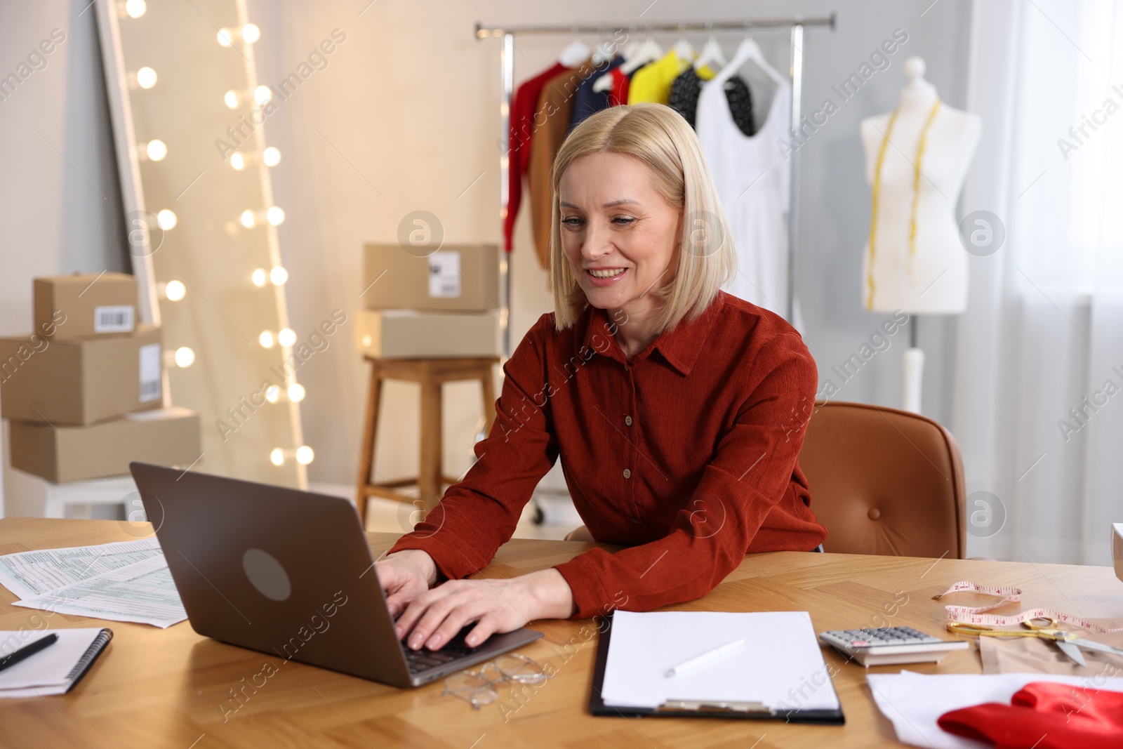 Photo of Business owner working on laptop at table in her tailor shop