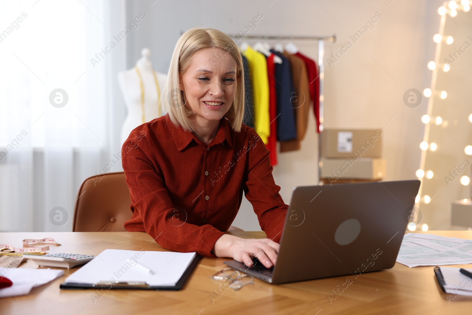 Photo of Business owner working on laptop at table in her tailor shop