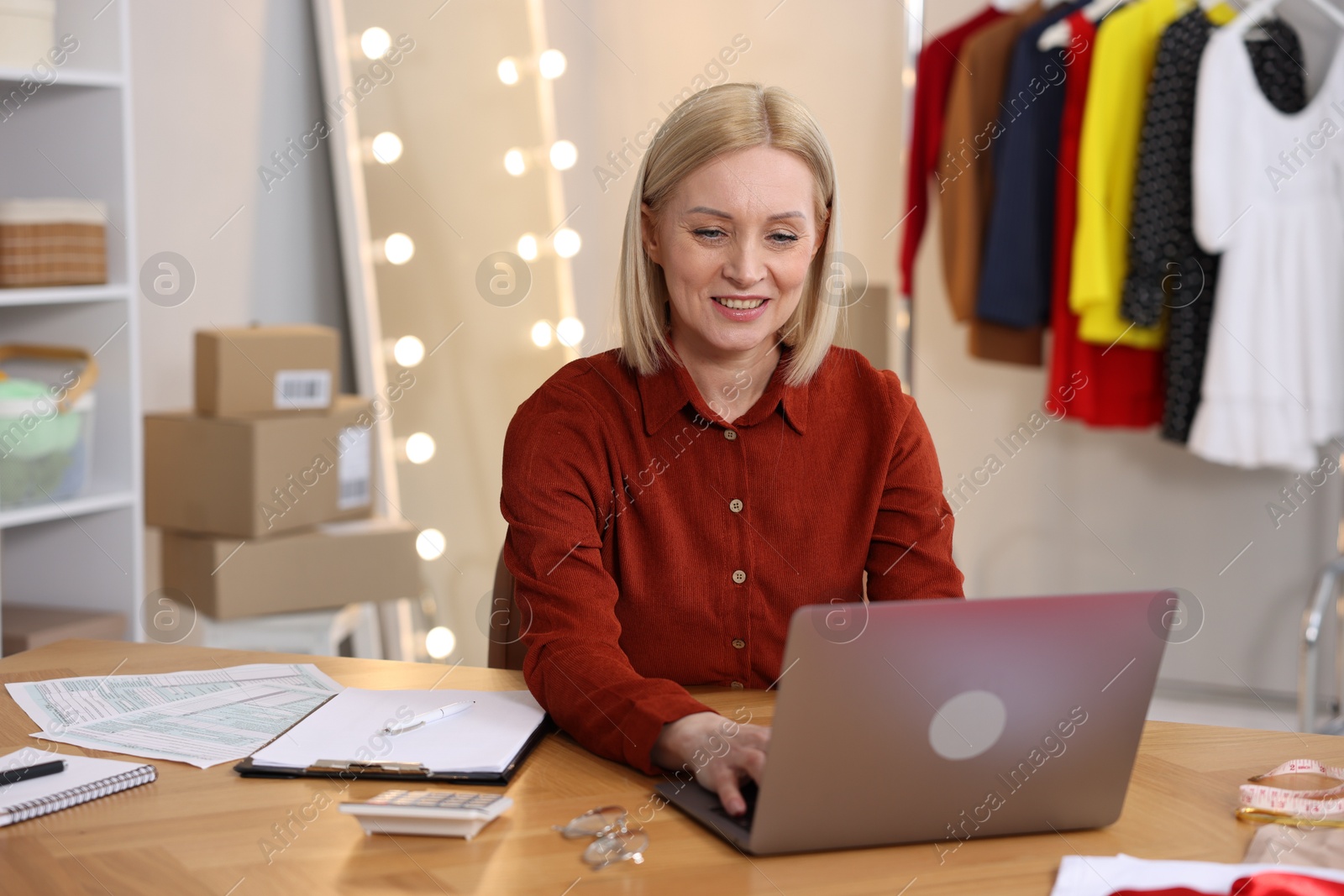 Photo of Business owner working on laptop at table in her tailor shop