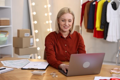 Photo of Business owner working on laptop at table in her tailor shop