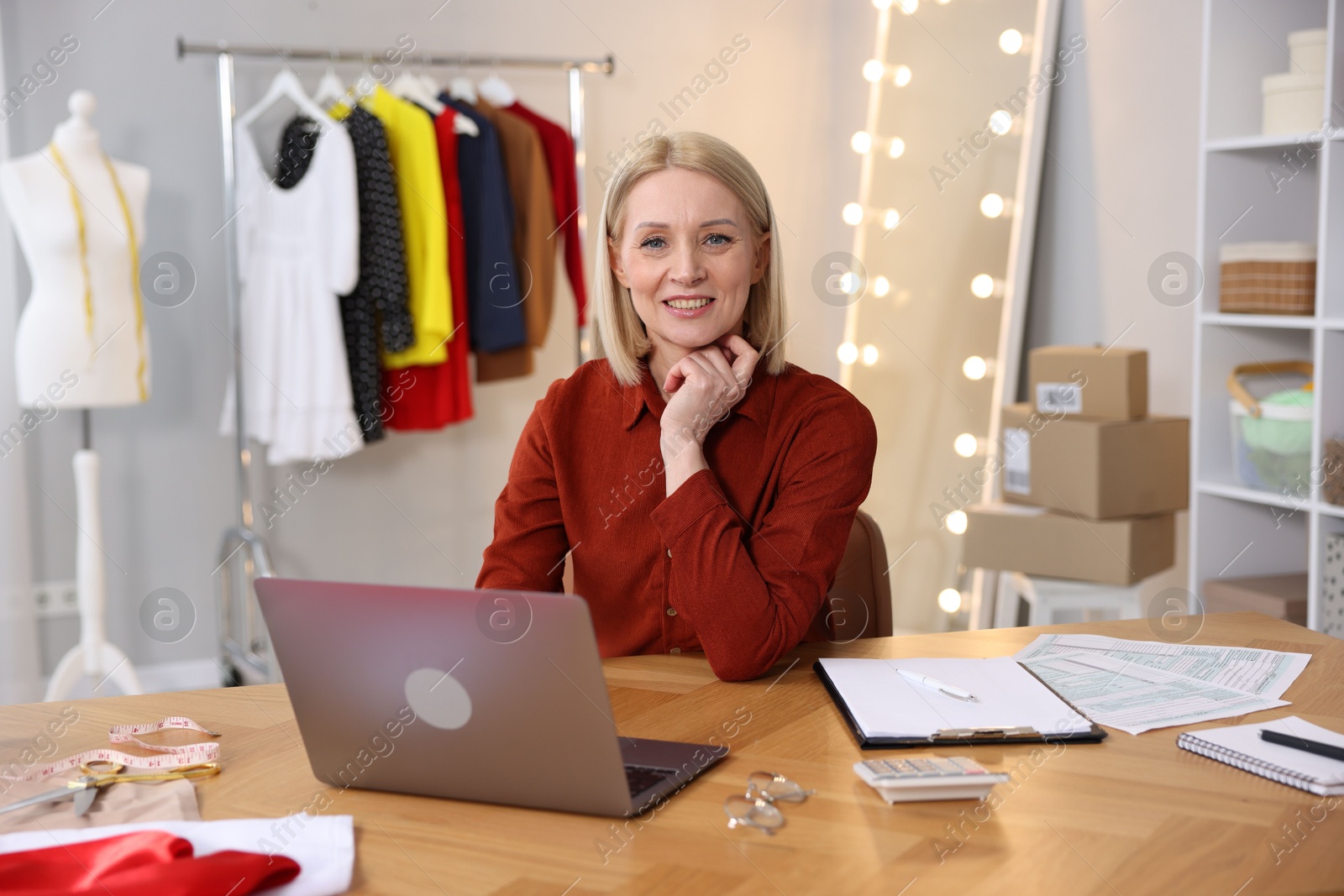 Photo of Business owner at table with laptop in her tailor shop