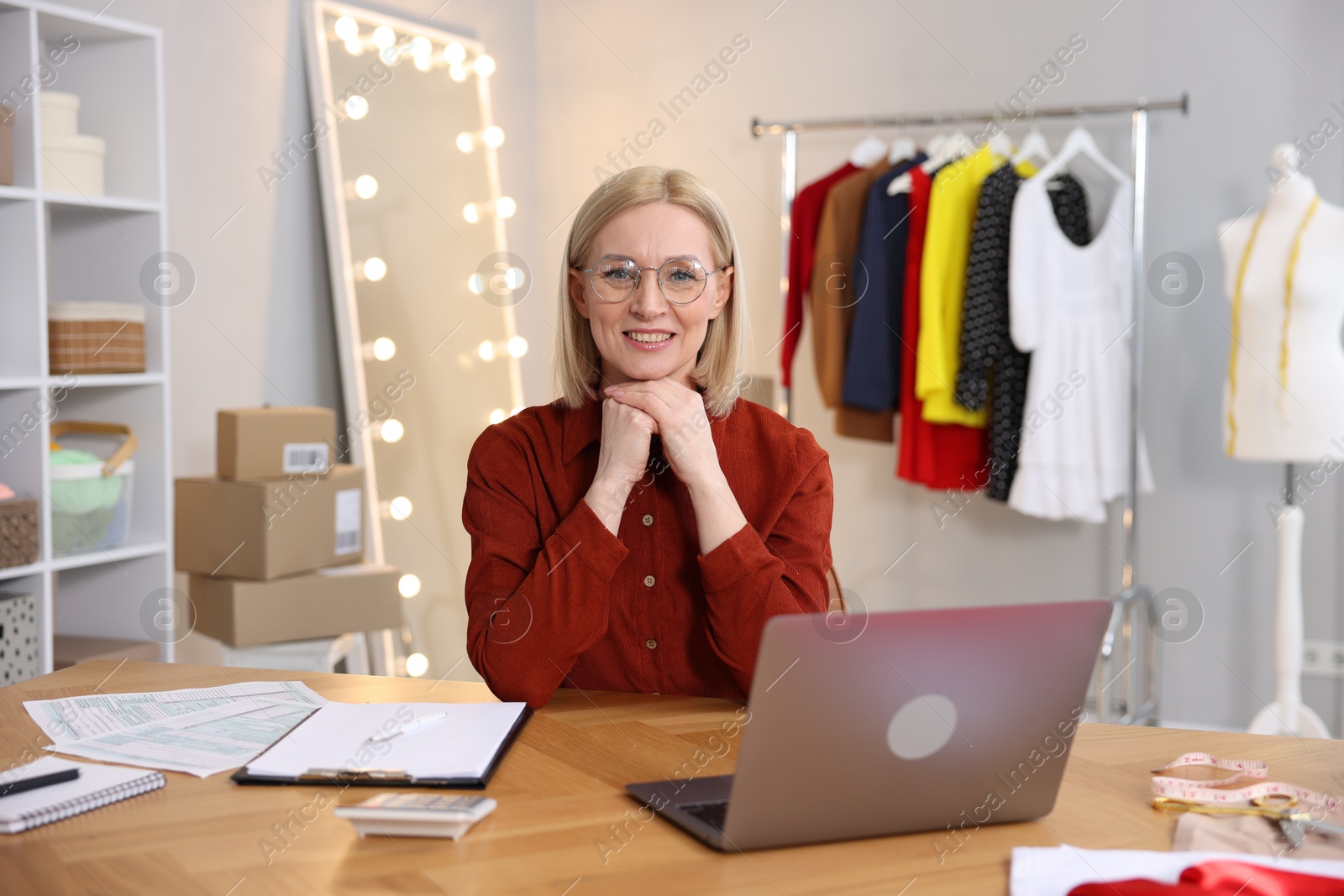 Photo of Business owner at table with laptop in her tailor shop