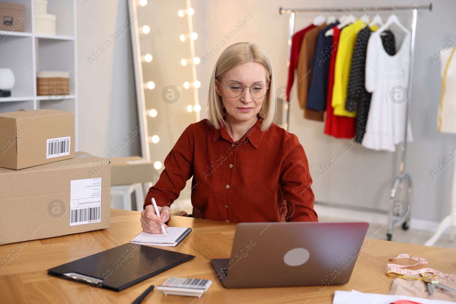 Photo of Business owner taking notes at table in her tailor shop