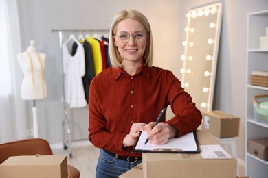 Photo of Business owner taking notes near parcels in her tailor shop