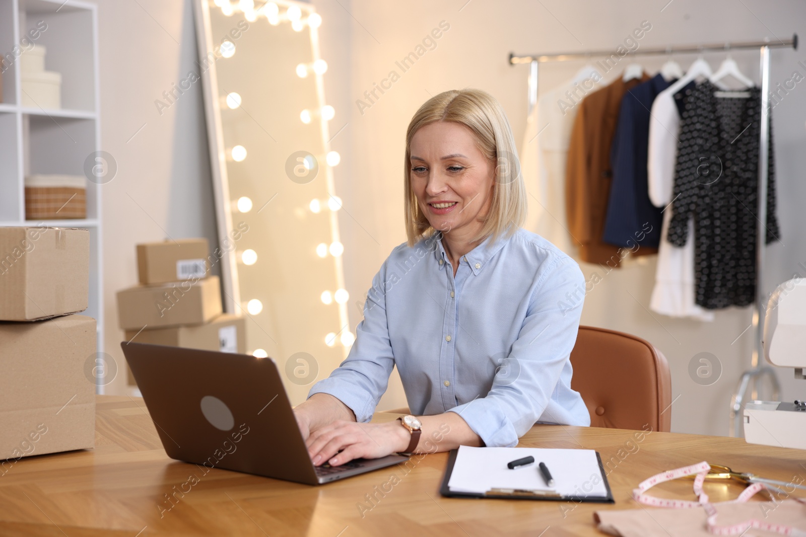 Photo of Business owner working on laptop at table in her tailor shop