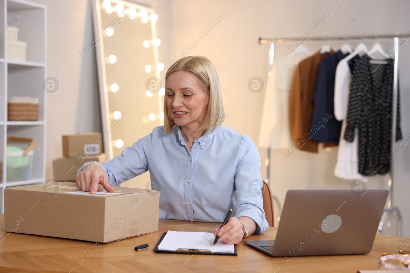 Photo of Business owner taking notes at table in her tailor shop