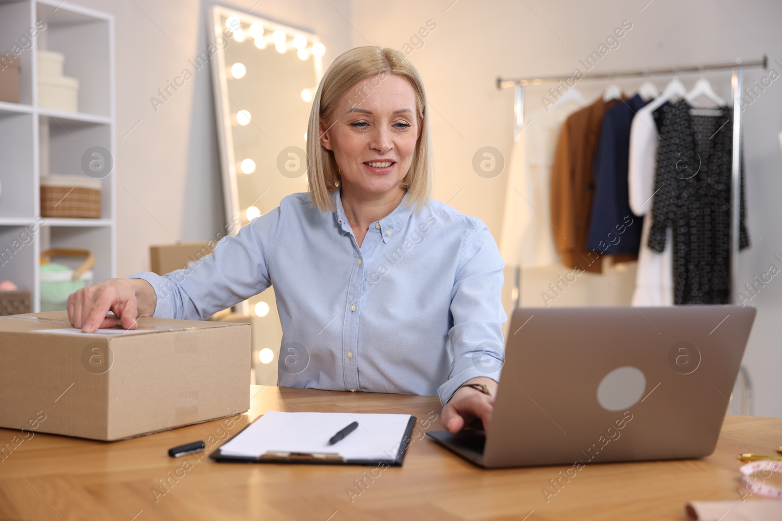 Photo of Business owner working on laptop at table in her tailor shop