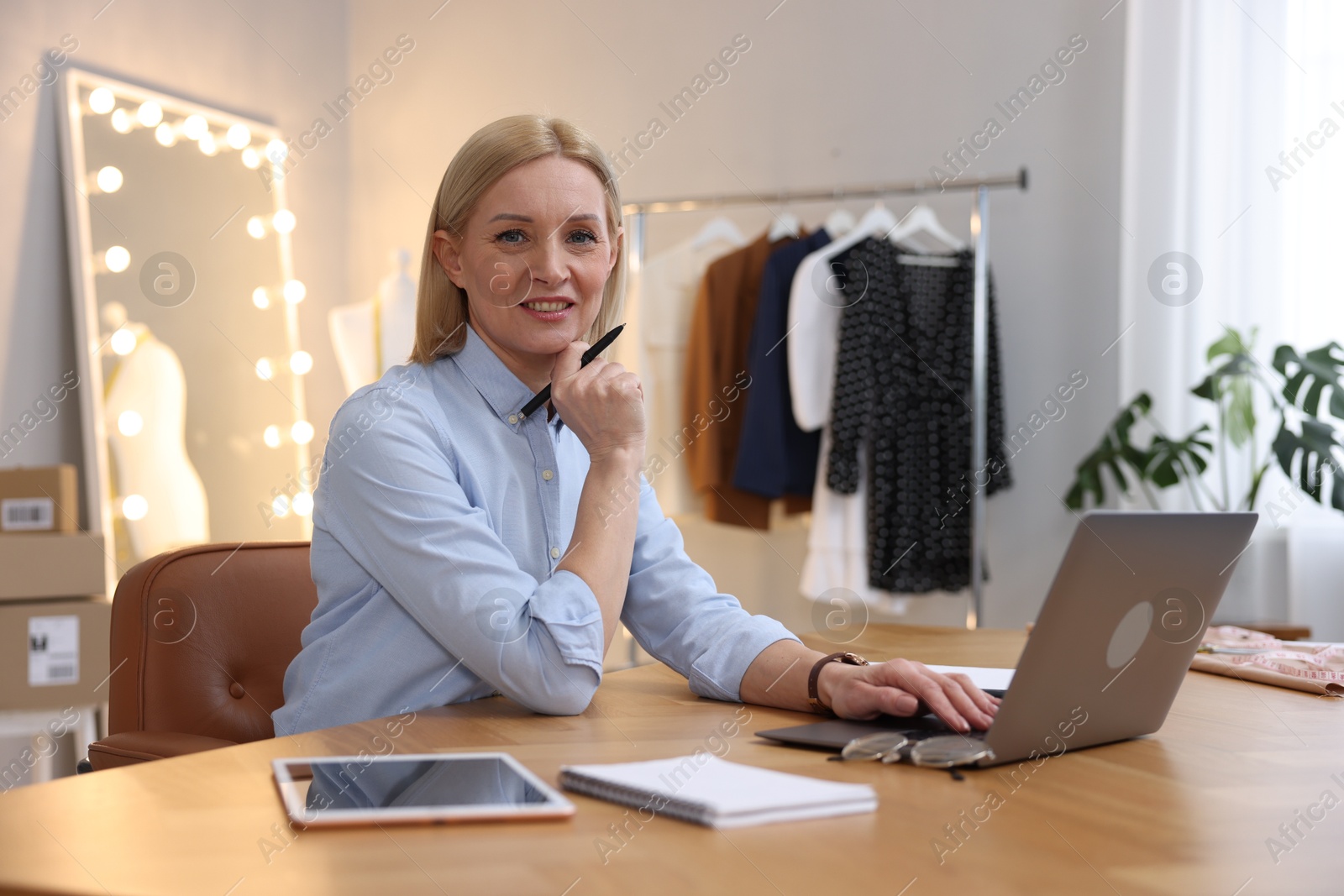 Photo of Business owner working on laptop at table in her tailor shop