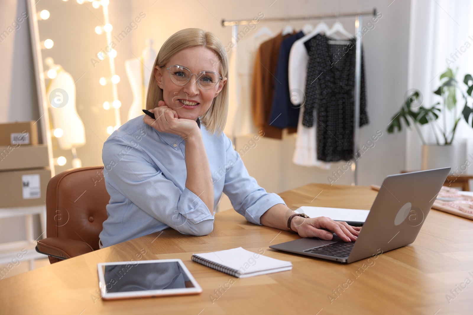 Photo of Business owner working on laptop at table in her tailor shop