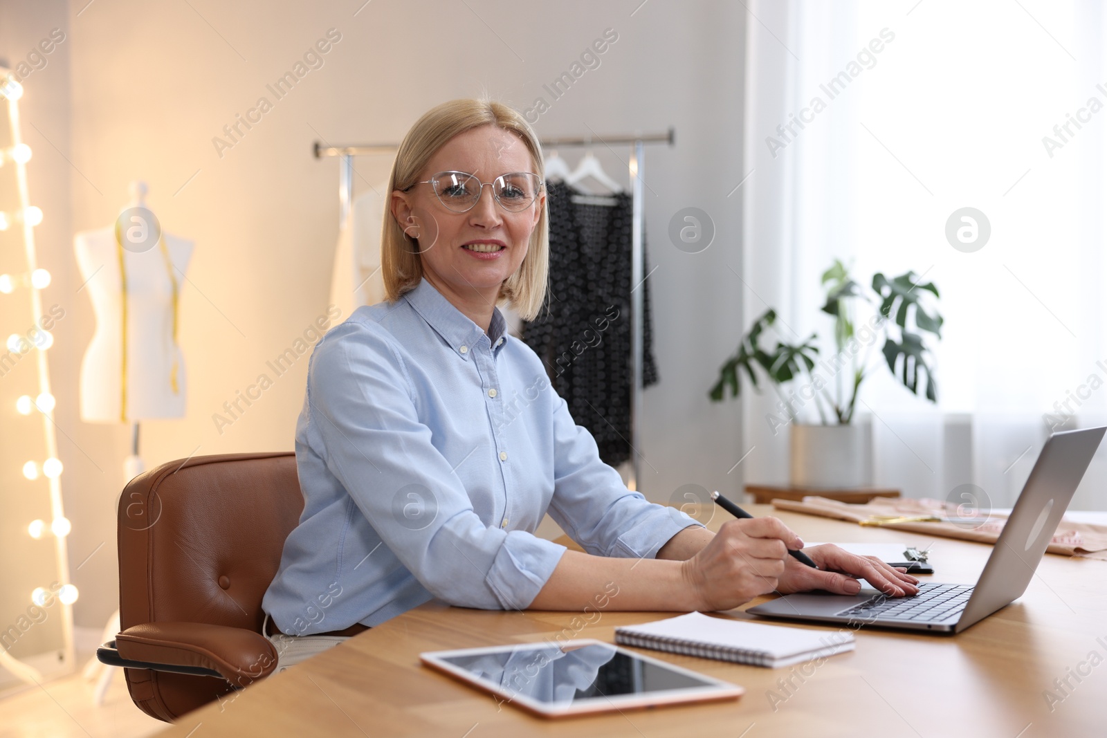 Photo of Business owner working on laptop at table in her tailor shop