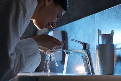 Woman washing her face over sink in bathroom