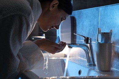 Photo of Woman washing her face over sink in bathroom