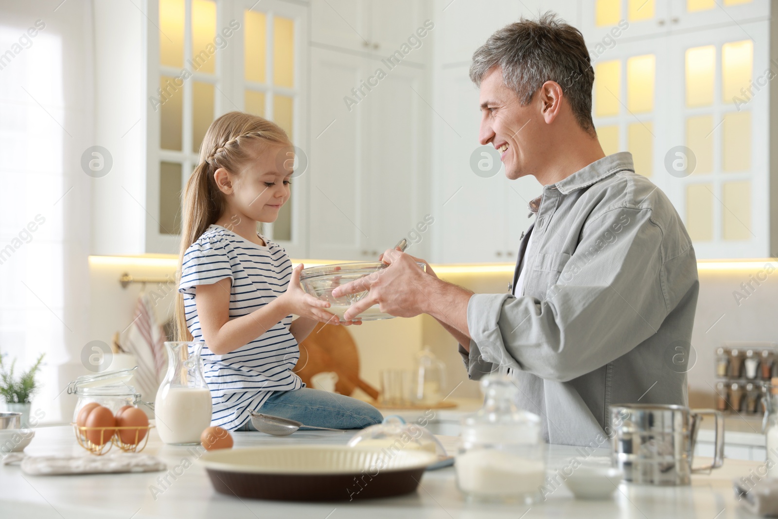 Photo of Father and his daughter making dough in kitchen