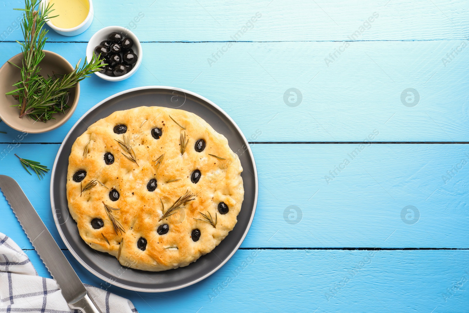 Delicious focaccia bread with olives, rosemary and oil on light blue wooden table, flat lay. Space for text Photo of Delicious focaccia bread with olives, rosemary and oil on light blue wooden table, flat lay. Space for text