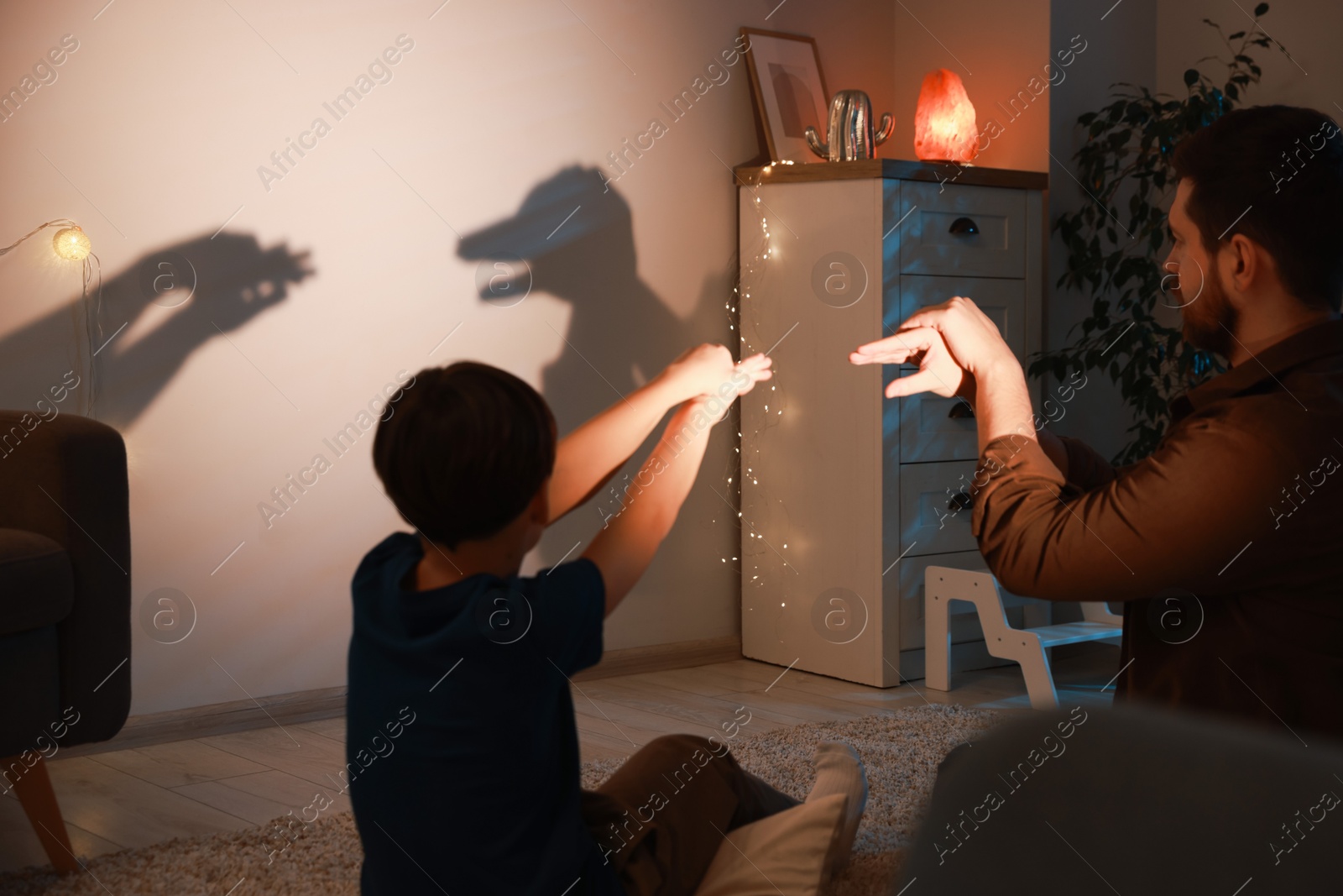 Photo of Father and his son performing shadow play at home