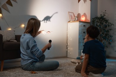 Photo of Mother performing shadow play with toy dinosaur to her kids at home