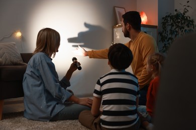 Photo of Man making hand gesture like dog while performing shadow play to his family at home