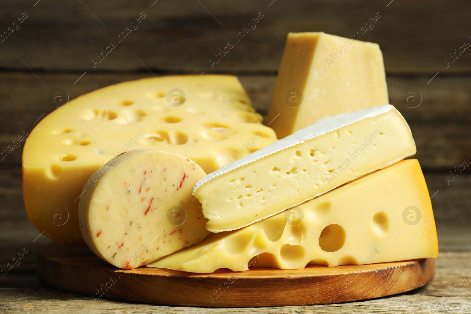 Photo of Different types of cheese on wooden table, closeup