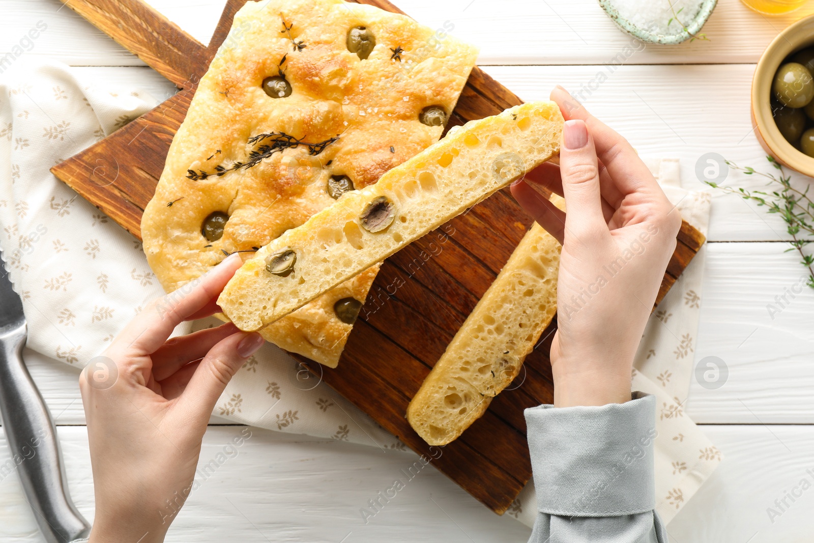 Woman with piece of delicious focaccia bread at white wooden table, top view Photo of Woman with piece of delicious focaccia bread at white wooden table, top view