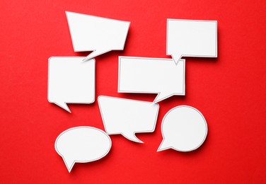 Photo of Blank speech bubbles on red background, top view. Space for text