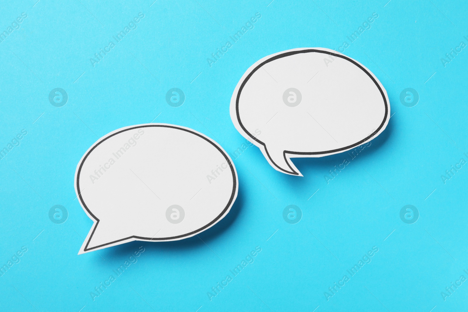 Photo of Blank speech bubbles on light blue background, top view. Space for text