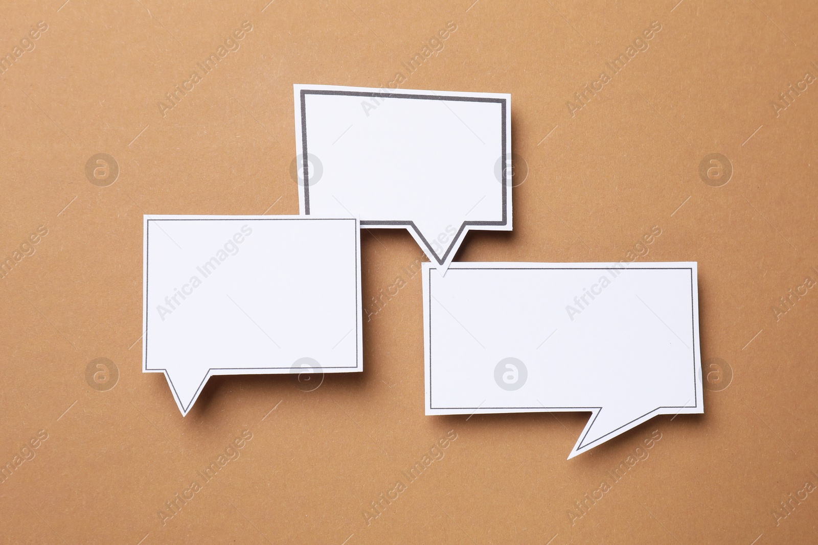 Photo of Blank speech bubbles on brown background, top view. Space for text