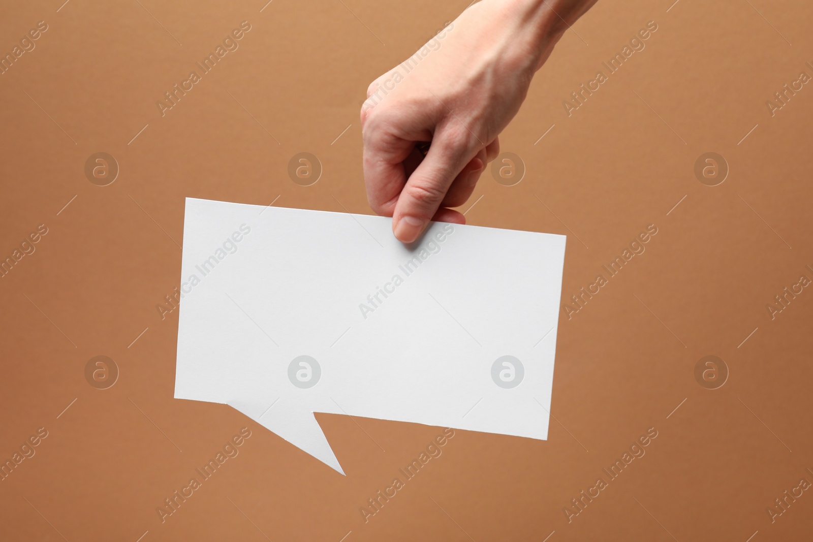 Photo of Woman holding blank speech bubble on brown background, closeup. Space for text