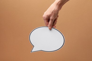 Photo of Woman holding blank speech bubble on brown background, closeup. Space for text