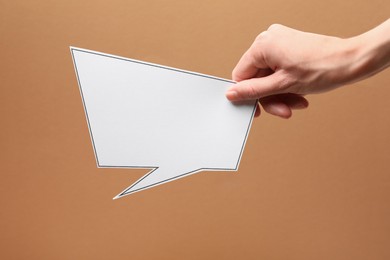 Photo of Woman holding blank speech bubble on brown background, closeup. Space for text