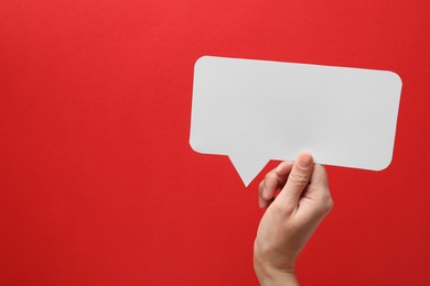 Photo of Woman holding blank speech bubble on red background, closeup. Space for text