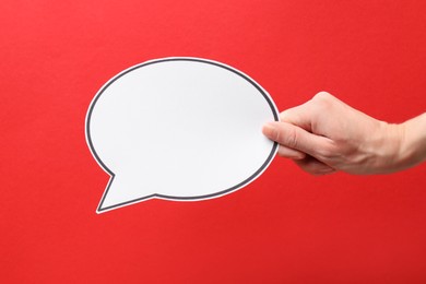 Photo of Woman holding blank speech bubble on red background, closeup. Space for text