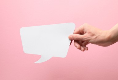 Photo of Woman holding blank speech bubble on light pink background, closeup. Space for text